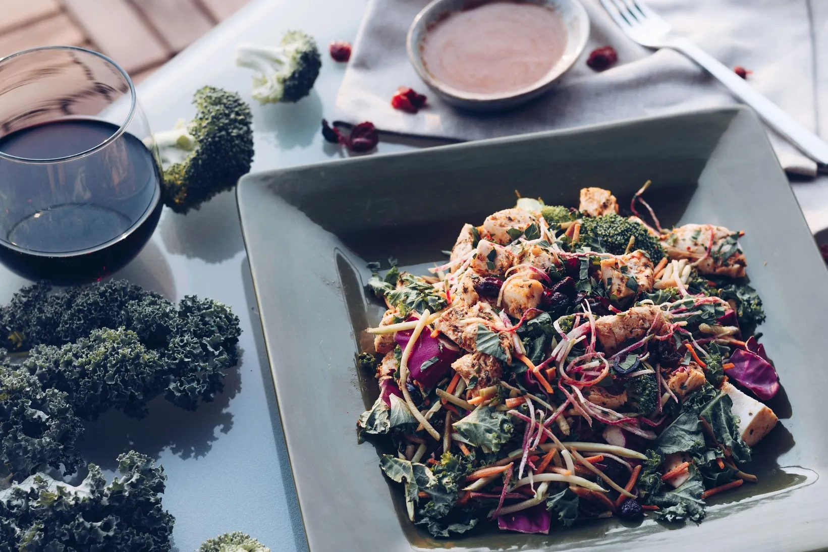 Mixed vegetable salad with leafy greens, broccoli, shredded vegetables, and dressing served in a bowl